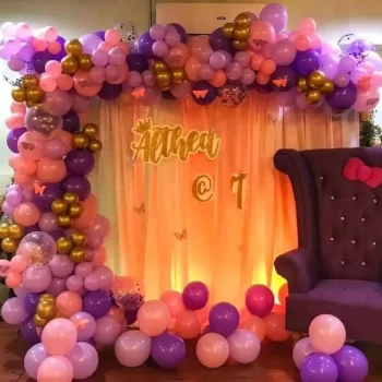 Colourful balloon-decorated birthday backdrop with elegant purple chair and lighted curtain, perfect for a children's birthday celebration by Dream Tent House, tent rental service in Bangalore.